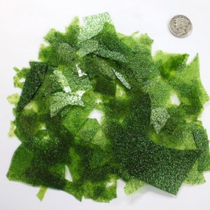 May include: A pile of green glitter confetti. The confetti is made of thin, translucent plastic and has a sparkly finish.