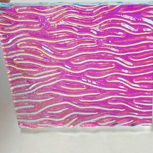 May include: A rectangular piece of iridescent material with a wavy pattern. The colors shift from pink to purple with white and yellow highlights, creating a shimmering effect. The material appears to be translucent.