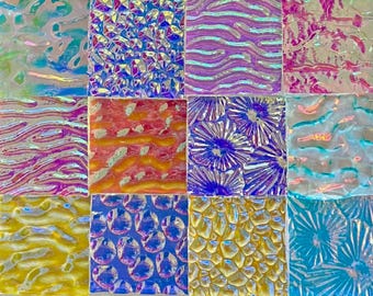 May include: A grid of twelve square glass tiles featuring various iridescent textures and patterns, including wavy lines, circular bubbles, floral motifs, and geometric shapes in vibrant colours like blue, purple, yellow, pink, and orange.
