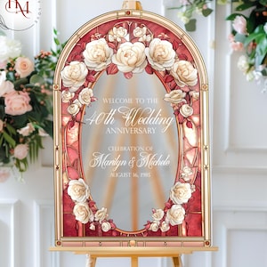 May include: A decorative wedding anniversary sign with a stained-glass effect. The sign features a floral design with white roses and the text "Welcome to the 40th Wedding Anniversary Celebration of Marilyn & Michele August 16, 1985."