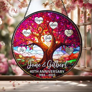 Peut inclure: Une fenêtre ronde en vitrail avec un motif d'arbre, avec des noms dans des feuilles en forme de cœur. La fenêtre commémore le 40e anniversaire de Jane & Gilbert, 1985-2025. L'arbre a un tronc brun et des feuilles roses et rouges vives.