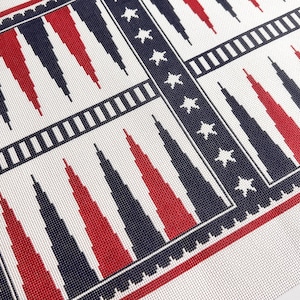 May include: A close-up of a backgammon board with a patriotic design. The board features alternating red and navy blue triangles against a white background, framed by navy blue borders with white stars.