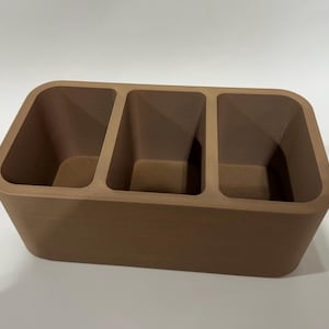 May include: A brown, rectangular, three-compartment organizer with rounded edges.