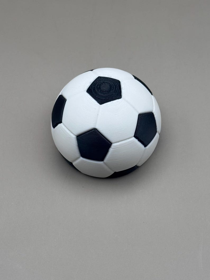 May include: A white and black soccer ball with a classic pentagon and hexagon pattern. The ball is a sphere, with black pentagons and white hexagons. The ball is a sports item.