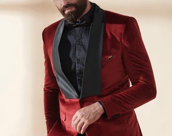 May include: A burgundy velvet blazer with a black satin lapel and a black bow tie. The blazer has a tailored fit and a single-button closure. The black shirt underneath has a textured pattern. The image is of a formal suit.
