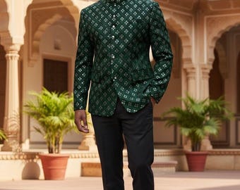 Puede incluir: Un hombre con una chaqueta verde oscuro estampada con cuello mandarín y pantalones negros. La chaqueta tiene un diseño floral blanco repetido. Lleva zapatos de vestir de cuero marrón.