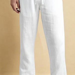Könnte beinhalten: Weiße Leinenhose mit Kordelzugbund. Die Hose hat eine lockere Passform und ein gerades Bein. Der Text "FASHION KURTA" ist unten im Bild aufgedruckt. Die Hose ist aus leichtem Stoff gefertigt.