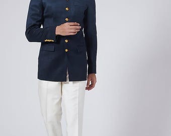 May include: A navy blue blazer with gold buttons and a mandarin collar is paired with white trousers. The blazer has a tailored fit and long sleeves. The outfit is completed with brown leather shoes.
