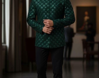 Puede incluir: Un hombre con una chaqueta verde oscuro estampada con cuello mao y pantalones negros. La chaqueta tiene un diseño floral sutil. El texto "KING MEN'S TAILOR" es visible en la parte inferior. El entorno es interior.