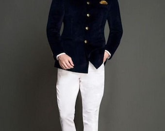 Op de afbeelding: Een marineblauwe fluwelen jas met gouden knopen en een opstaande kraag wordt gecombineerd met een witte broek en bruine schoenen. Een pochet maakt de outfit compleet. De tekst "FASHION KURTA" is zichtbaar.
