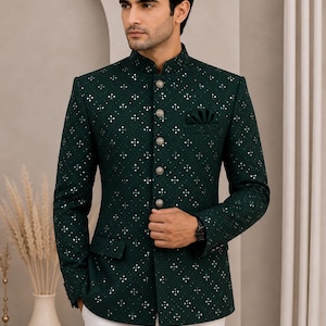 Könnte beinhalten: Eine dunkelgrüne Bandhgala-Jacke mit Stehkragen, langen Ärmeln und einem sich wiederholenden geometrischen Muster aus kleinen silbernen Metallverzierungen. Die Jacke hat fünf runde silberne Knöpfe auf der Vorderseite und ein Einstecktuch.