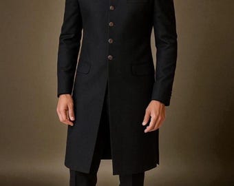 May include: A black, long-line suit jacket with a mandarin collar and a row of brown buttons. A gold pocket square is visible in the chest pocket. The jacket is paired with black trousers, creating a formal ensemble.