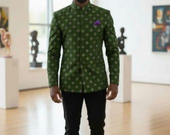 Puede incluir: Un hombre con una chaqueta verde estampada con cuello mandarín, un pañuelo de bolsillo morado, pantalones negros y zapatos negros. La chaqueta tiene un diseño floral blanco repetido. El escenario es una galería de arte con esculturas y pinturas.