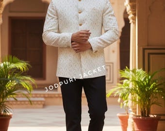 May include: A cream-colored Jodhpuri jacket with gold buttons and intricate embroidery, paired with black trousers. The image features the text "JODHPURI JACKET". The model is standing in a courtyard with potted plants.