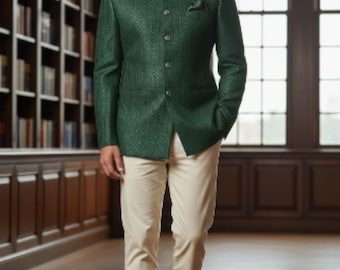 Puede incluir: Un hombre con una blazer verde oscuro texturizada con cuello mandarín, combinada con pantalones color crema y zapatos de cuero marrón. La blazer tiene un pañuelo de bolsillo. El escenario es una biblioteca con estanterías y ventanas arqueadas.