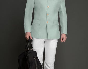 Op de afbeelding: Lichtgroene jas met een opstaande kraag en gouden knopen, gecombineerd met een witte broek. Een bordeauxrode pochet is zichtbaar. Een zwarte weekendtas wordt in de linkerhand gehouden. De tekst "FASHION KURTA" staat onderaan.