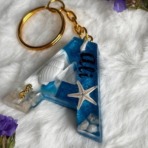 Llavero de resina con letra de playa personalizado: llavero epoxi inspirado en el océano con conchas, estrellas de mar y nombre. Regalo con inicial hecho a mano.