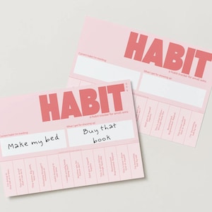 May include: Two pink habit trackers with the word "HABIT" in large red letters. The top tracker has the text "When I get for achieving this" and the bottom tracker has the text "What I get for achieving this" with the handwritten text "Buy that book" and "Make my bed".