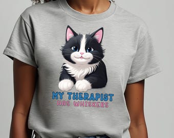 May include: A gray t-shirt with a black and white cartoon cat and the text "My therapist has whiskers".