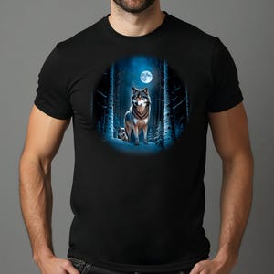 May include: Black t-shirt featuring a circular graphic of two wolves in a snowy forest under a full moon. The wolves have gray and brown fur, and the forest is depicted with white snow and tall trees.