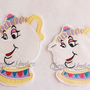 May include: Two embroidered iron-on patches of Mrs. Potts from Disney's Beauty and the Beast. The larger patch is approximately 4 inches tall and the smaller patch is approximately 3 inches tall. Both patches feature a white teapot with a purple and yellow trim, pink and blue accents, and a smiling face.