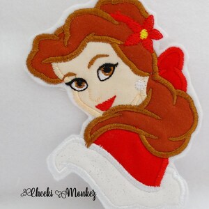 May include: Embroidered patch featuring a cartoon image of a woman with brown hair, red bow, and red flower. The woman is wearing a red dress with a white collar. The patch has a white border and the text "Cheeki Monkey" in cursive.