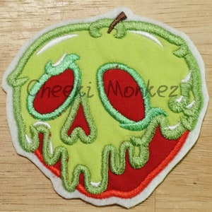 May include: Green apple with a red skull face and dripping green and white icing. The apple is outlined in white and red.