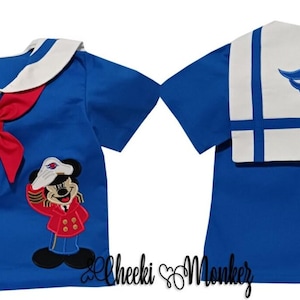 May include: A blue sailor-style shirt with a white collar and red bow. The front features an embroidered Mickey Mouse in a sailor outfit. The back has a white panel with a red Mickey Mouse emblem and blue stripes. The shirt is a children's garment.