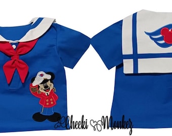 Puede incluir: Una camiseta azul de estilo marinero con cuello blanco y lazo rojo. La parte delantera presenta un Mickey Mouse bordado con un atuendo de marinero. La parte trasera tiene un panel blanco con un emblema de Mickey Mouse rojo y rayas azules. Ropa infantil.