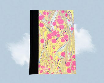 Puede incluir: Un diario de tapa dura con un diseño veteado. La cubierta presenta un patrón vibrante de remolinos rosas, amarillos, azules y blancos. El lomo es negro liso. El diario es rectangular y parece nuevo.