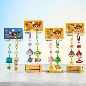 Puede incluir: Ocho llaveros de personajes de Toy Story sujetos a cuatro tarjetas de presentaci&oacute;n de cart&oacute;n. Cada llavero incluye una figura de pl&aacute;stico, un lazo peque&ntilde;o y un dije secundario, con personajes como Buzz Lightyear, Rex y Woody.