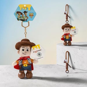Puede incluir: Un llavero de peluche de Woody de Toy Story 5 con sombrero de vaquero marr&oacute;n, camisa de cuadros amarilla, chaleco con estampado de vaca, pantalones azules y capa roja. Incluye una cadena dorada, una etiqueta hexagonal Potdemiel y una tarjeta.