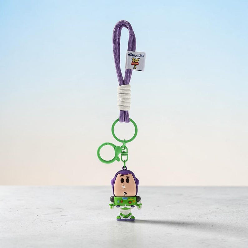 Puede incluir: Un llavero de cord&oacute;n morado con un peque&ntilde;o dije del personaje Buzz Lightyear. El cord&oacute;n tiene un detalle envuelto en blanco y una peque&ntilde;a etiqueta blanca con el logotipo de Disney Pixar Toy Story 5. Incluye una argolla y un mosquet&oacute;n verdes.