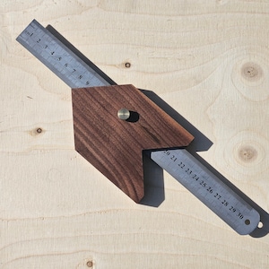 Op de afbeelding: Een houten combi-vierkant met een donkerbruin lichaam en twee metalen linialen. Eén liniaal is gemarkeerd in centimeters, de andere tot 30 cm. Het vierkant ligt op een licht houten oppervlak.