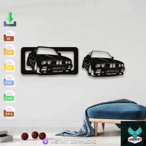 May include: Black car silhouette wall art. One car is framed in a rectangle, the other is separate. Both cars have the text "06 KNN 325" on the license plate. The wall art is a laser cut design.