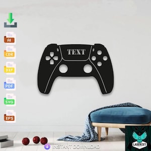 May include: Black wall art in the shape of a video game controller with the word "TEXT" across the top. The controller has a symmetrical design with buttons and directional pads. The art is mounted on a white wall.