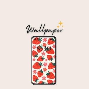 May include: A smartphone displaying a strawberry-themed wallpaper. The wallpaper features red strawberries and pink flowers on a white background. The word "Wallpaper" is written in a cursive font above the phone.
