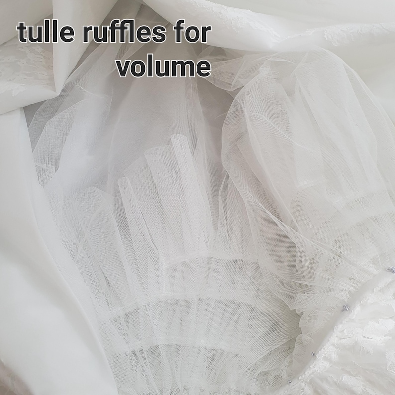 May include: Close-up of white tulle fabric with multiple layers and ruffles. The text "tulle ruffles for volume" is visible. The fabric appears to be part of a dress or skirt, designed to add fullness.