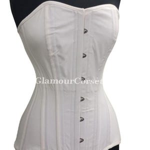 May include: A white corset with vertical stitching and a row of metal clasps down the front. The corset is displayed on a black mannequin. The text "GlamourCorset" is visible on the garment.