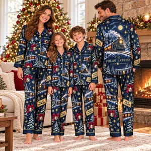 May include: Matching navy blue pajama sets featuring a Polar Express train print, snowy pine trees, golden stars, and red bows. The button-down shirts have collars and long sleeves, paired with matching long pants, all displaying the text The Polar Express.