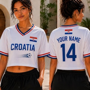 May include: A white V-neck crop top featuring the text CROATIA, a soccer ball graphic, and the Croatian flag on the front. The back displays the text YOUR NAME above the number 14 and a small Croatian flag. The sleeves have red and blue trim.