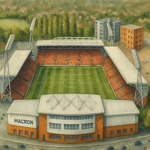 May include: An aerial view of a soccer stadium with a green field and red seats. The stadium has a white roof with a large sign that reads "MACRON". There are houses and trees in the background.