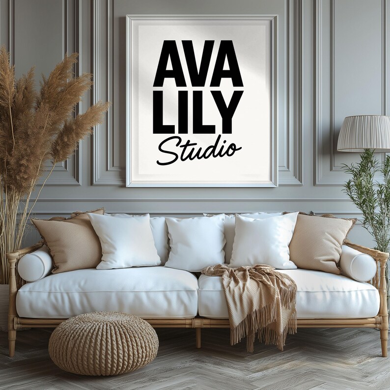 a modern living room with a white sofa, a woven ottoman, and a framed sign that reads "AVA LILY STUDIO" above the sofa.