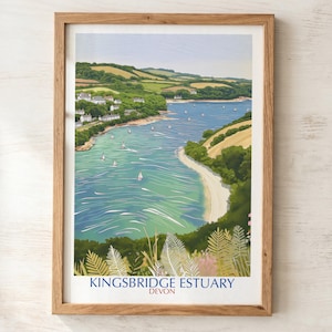 May include: A framed art print of the Kingsbridge Estuary in Devon, featuring a blue waterway with small sailboats, green rolling hills, and white buildings along the shore. The bottom of the print displays the text Kingsbridge Estuary Devon.