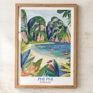 May include: A framed art print featuring a tropical landscape of Phi Phi, Thailand. The illustration depicts towering limestone cliffs, a sandy beach, and turquoise water with several long-tail boats. Tropical foliage frames the foreground.