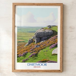 May include: A framed print of Dartmoor, Devon. The landscape depicts a rocky outcrop with purple heather and green grass. The background shows rolling green hills under a blue sky with white clouds. The print is in a wooden frame.