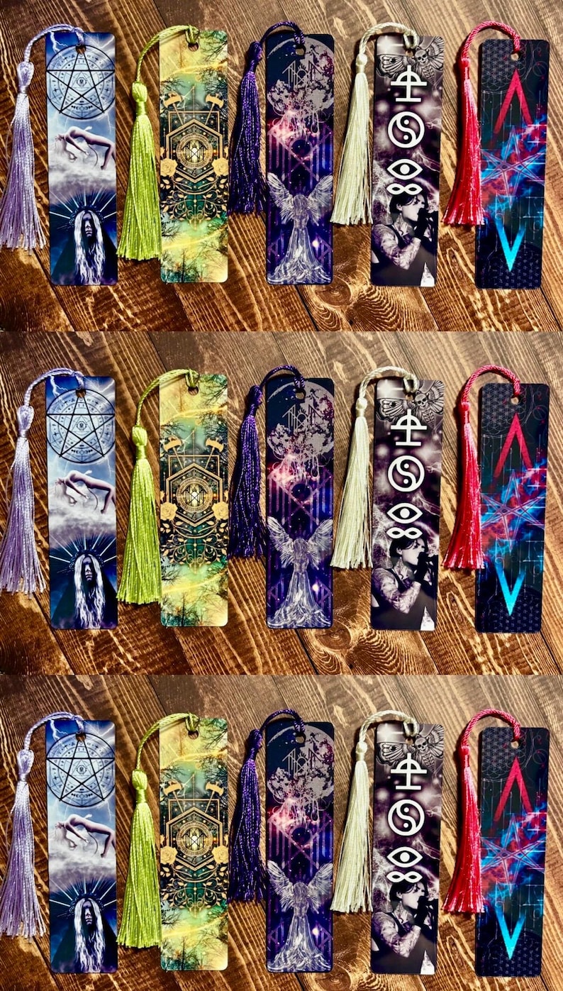 May include: A collection of decorative bookmarks with colorful designs and tassels. Each bookmark features unique artwork, including celestial symbols, angel figures, and abstract patterns. Tassels are in various colors, such as purple, green, and red.