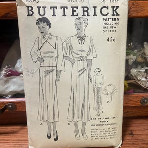May include: A vintage Butterick sewing pattern envelope, number 6390, size 20, 38 bust. The white paper envelope features black line illustrations of a one or two-piece frock with three sleeve styles, a gored skirt, and an inside belt at the natural waistline.