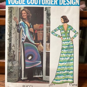 May include: A Vogue Couturier Design sewing pattern envelope for a Pucci dress, number 2713. The front shows two illustrations of long-sleeved, V-neck dresses with abstract blue, green, and purple patterns, one featuring fringe trim and side slits.