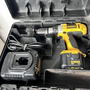 Puede incluir: Un juego de taladro inalámbrico y cargador DeWalt 12V XR amarillo y negro en un estuche de transporte negro. El taladro tiene un mango negro y una broca plateada. El cargador y el taladro son visibles.